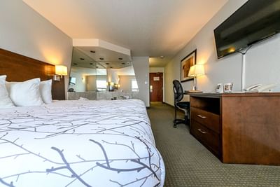 TV & work desk facing king bed in Spa Suite at Service Plus Inns & Suites