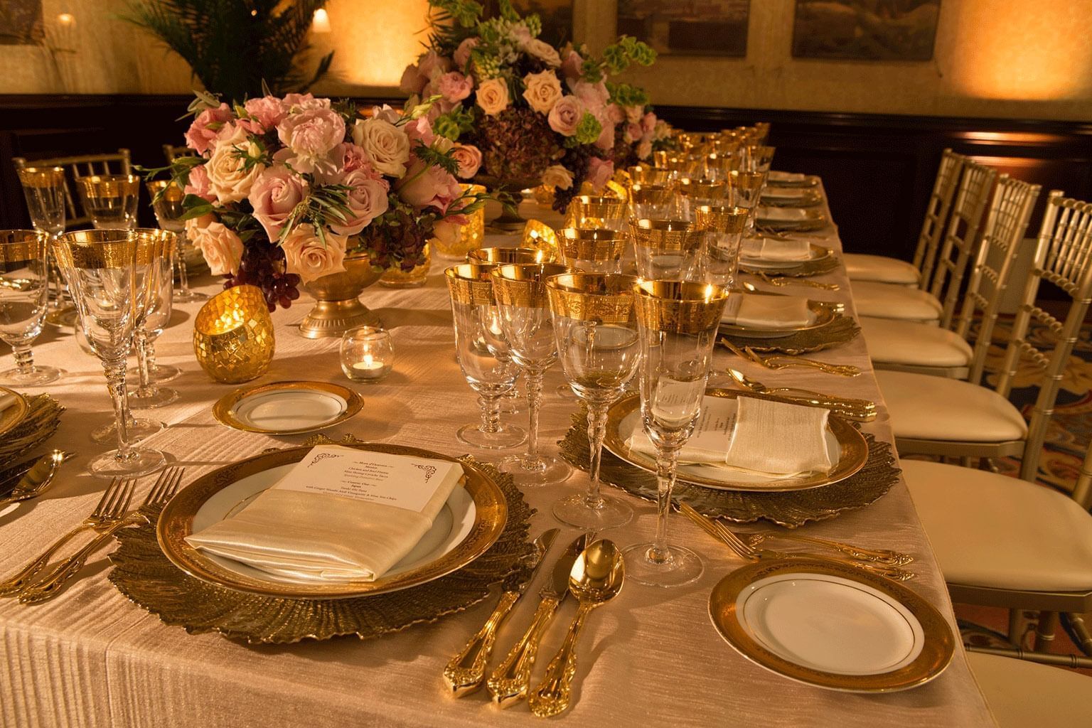 table decorated with gold place settings and roses