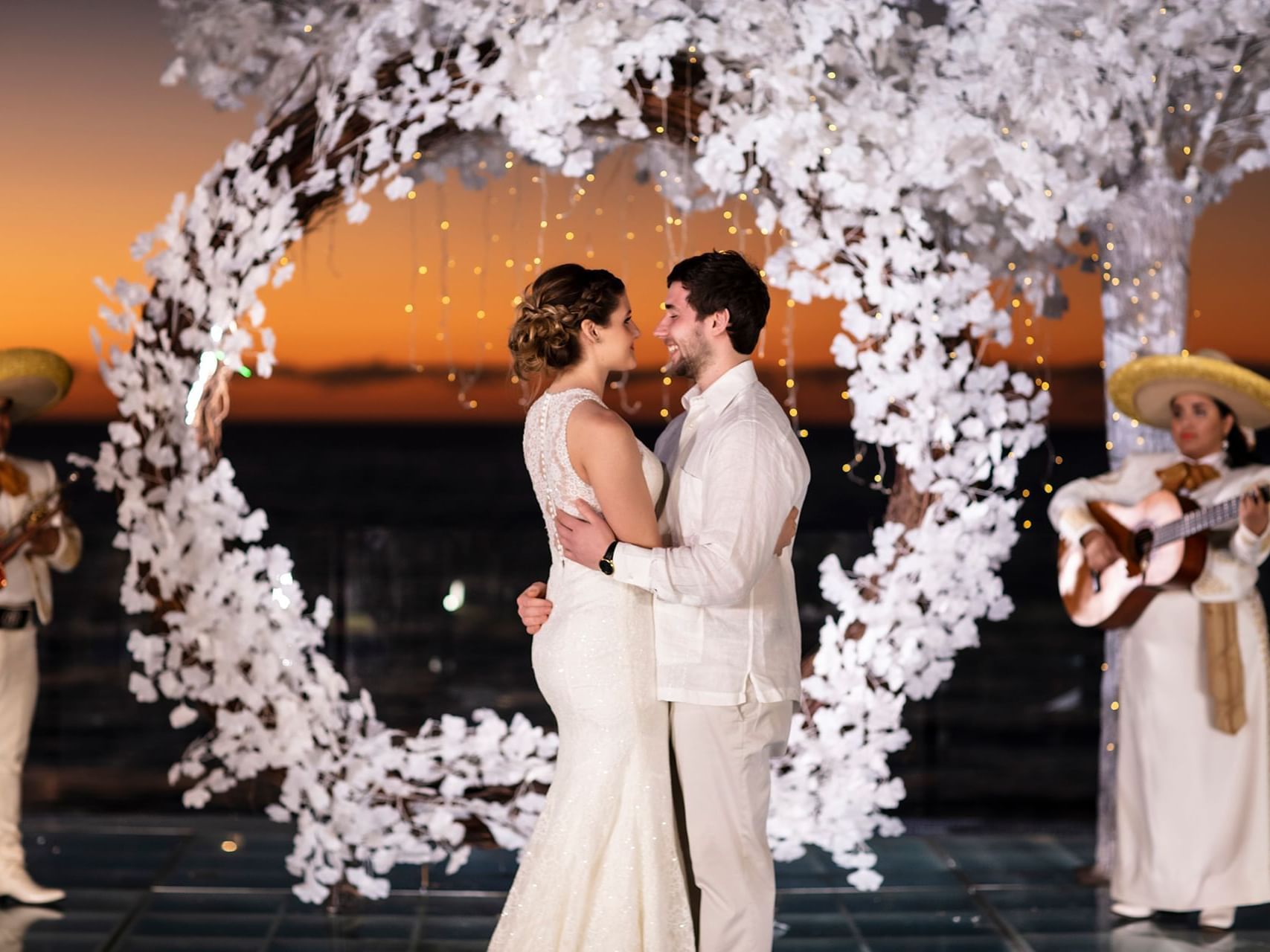 pareja en su boda al pie del mar con arco de flores blancas