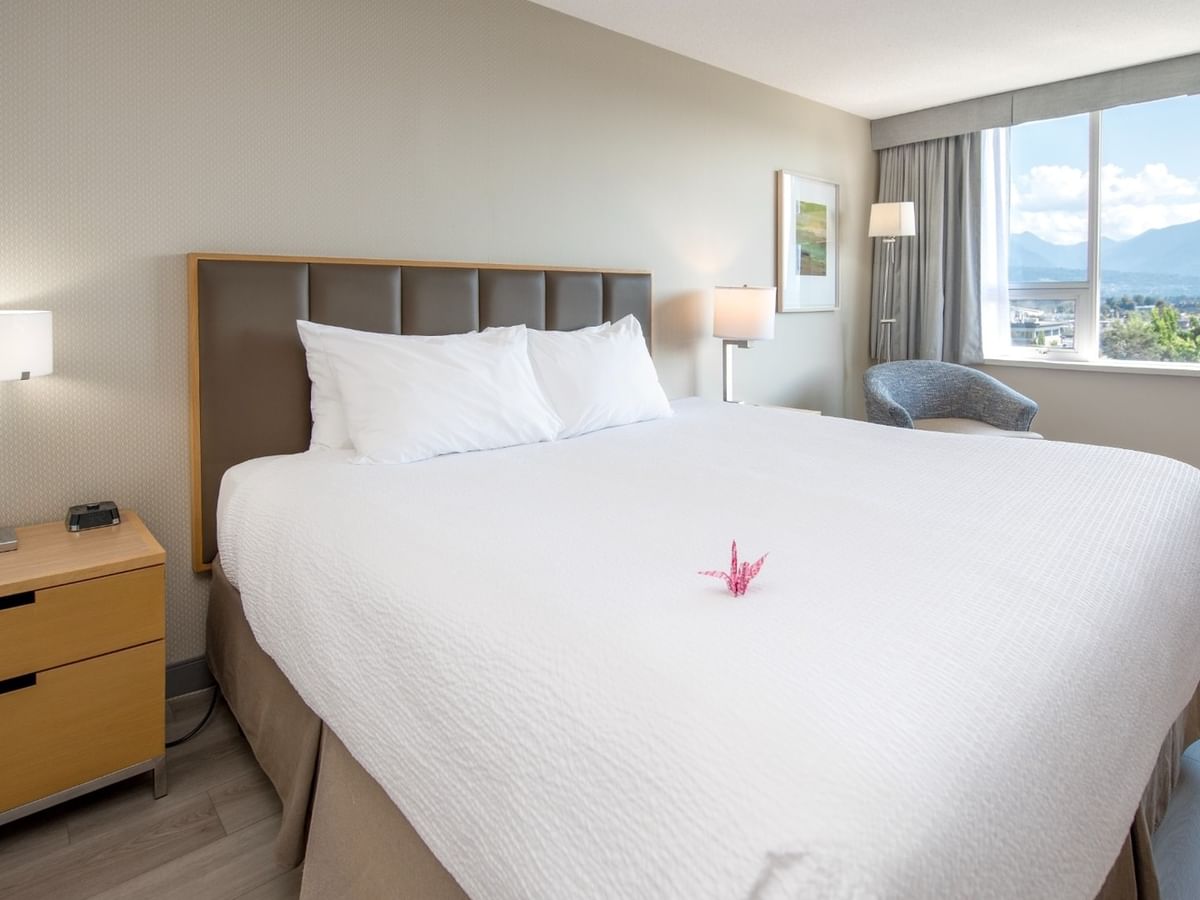 A hotel room with a king bed, large window, and pond view.