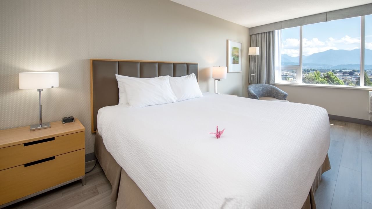 A hotel room with a king bed, large window, and pond view.