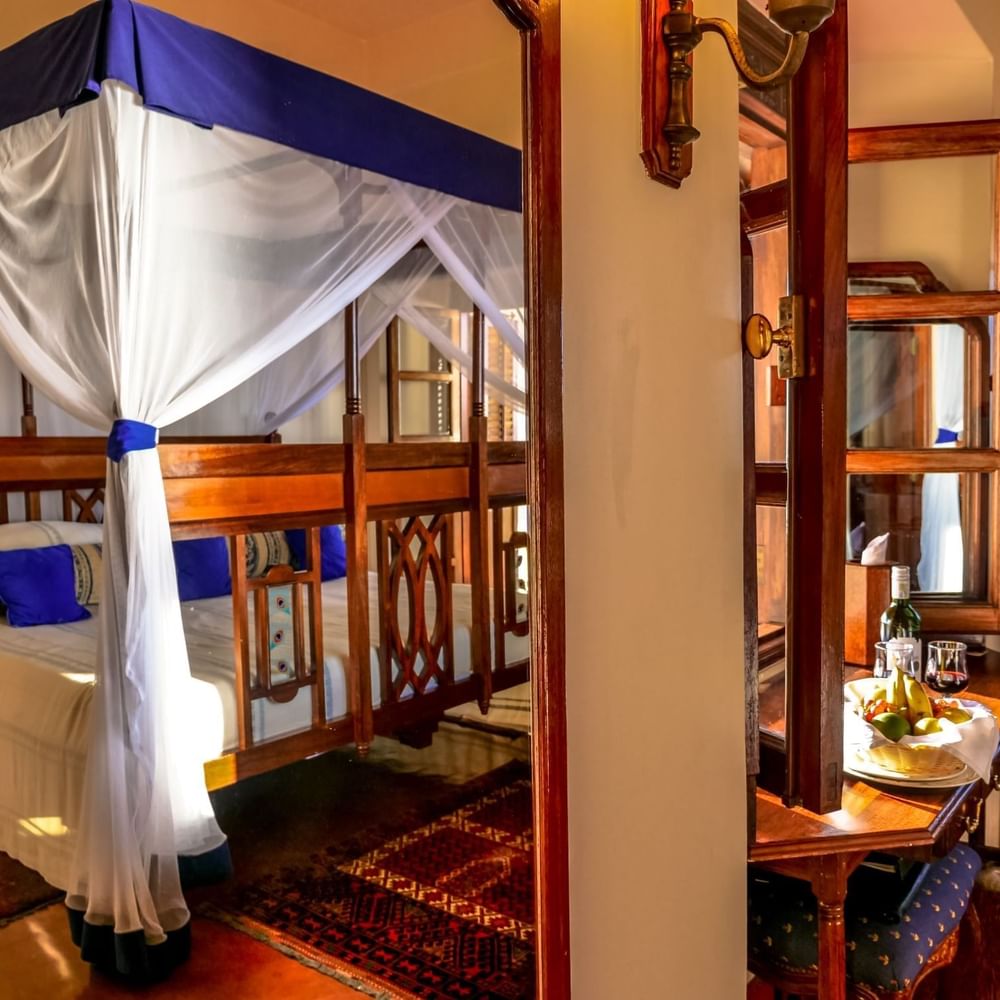 Cozy Prime King Room with canopy bed and fruit plate at Zanzibar Serena Hotel.