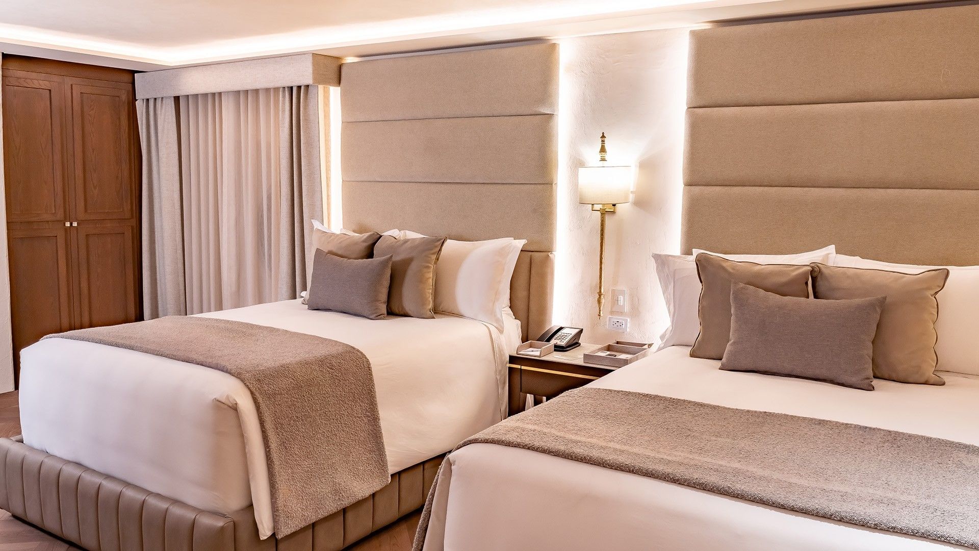 Two plush beds with tall padded headboards and warm integrated lighting in Two Double New Class at Quinta Real Puebla