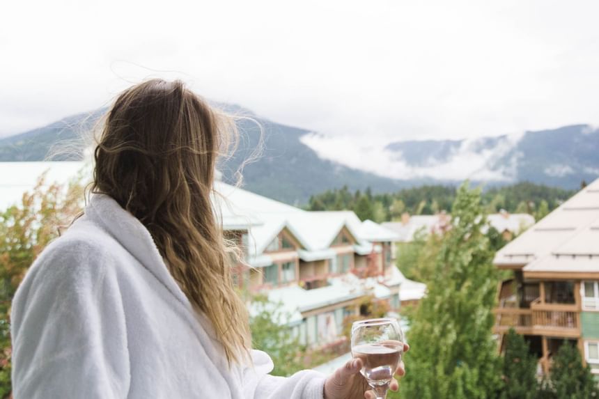 Woman in a white bathrobe standing on balcony at Summit Lodge