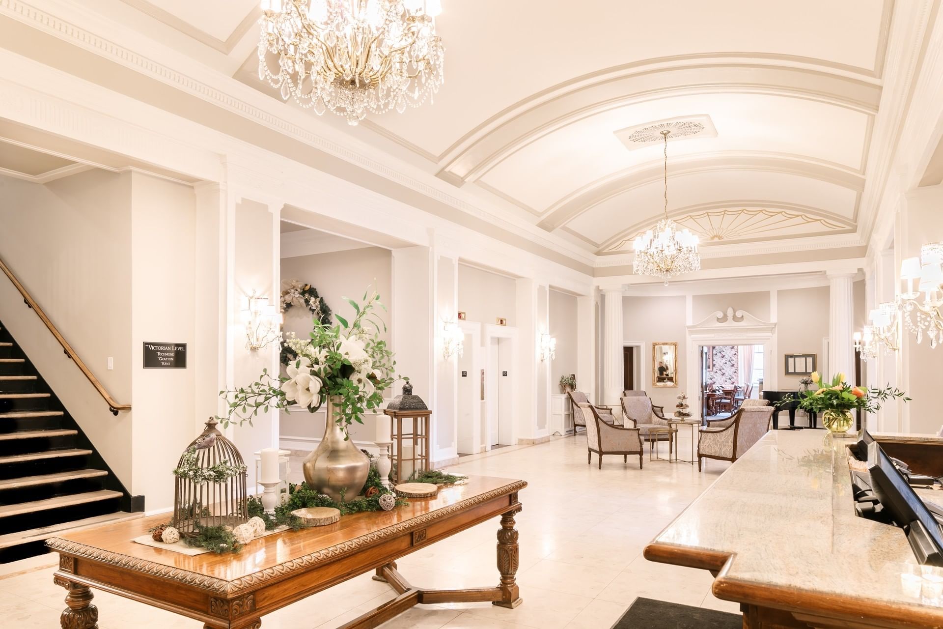 Elegant reception desk by a long wooden table under glowing chandeliers in a grand lobby at Rodd Charlottetown Hotel
