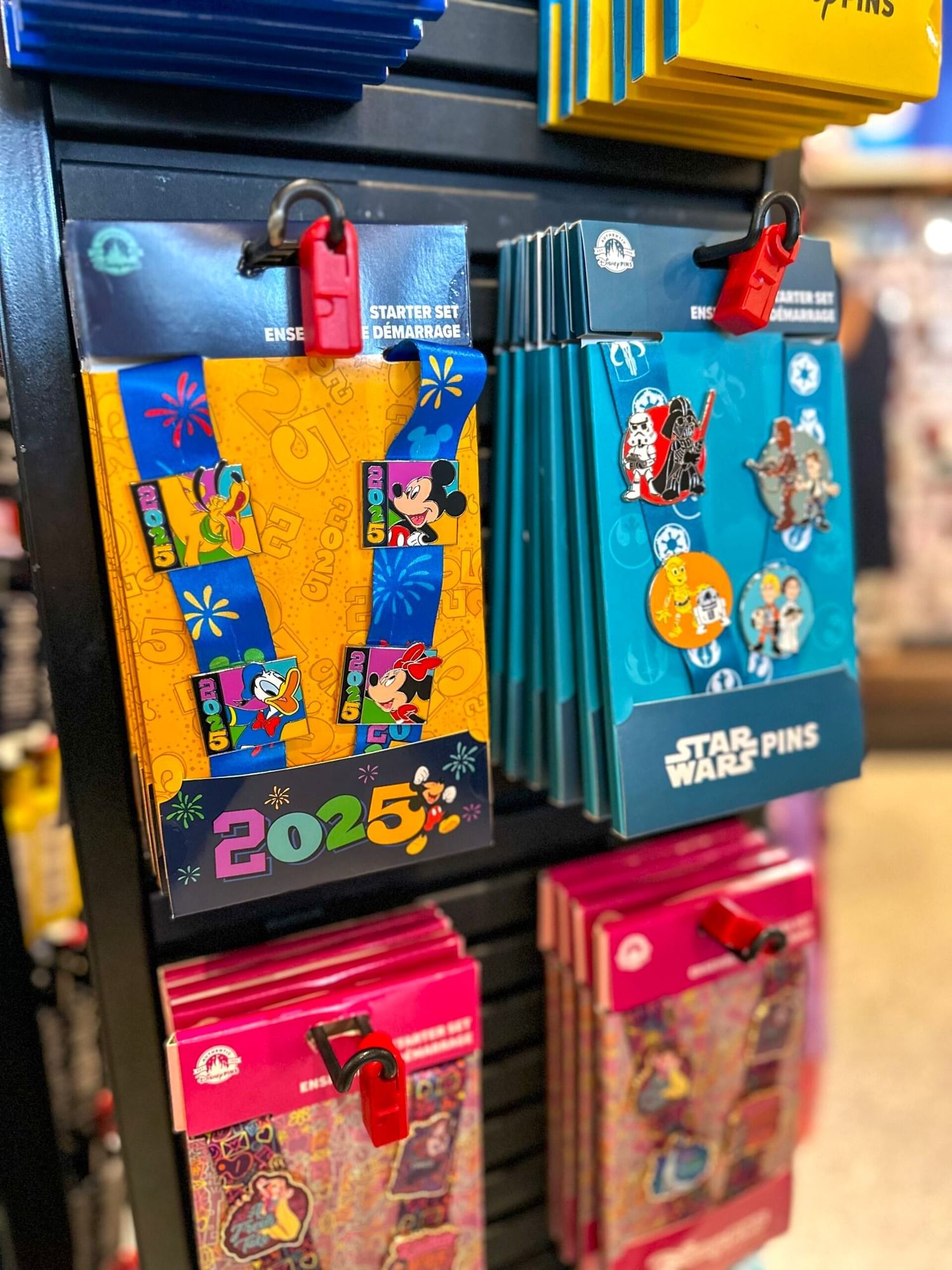 A display of four sets of collectable pins, including a 2025 commemorative set and a Star Wars set.