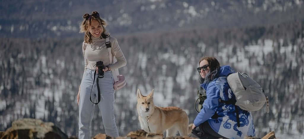 Two hikers with dog in snowy mountain setting
