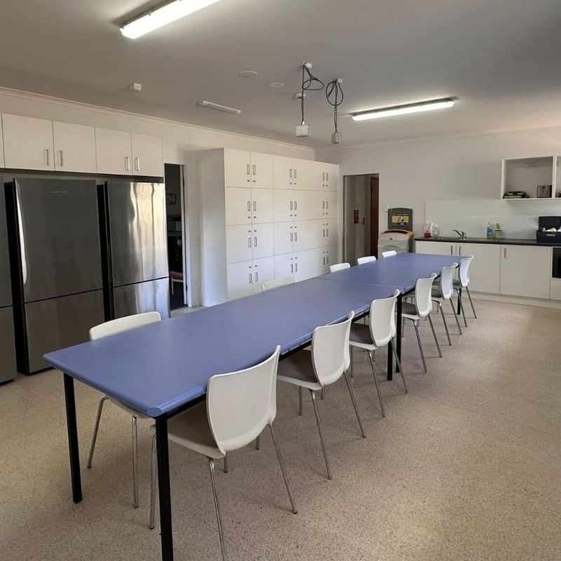 Long dining table and chairs in a kitchen at La Trobe University - Orde House.