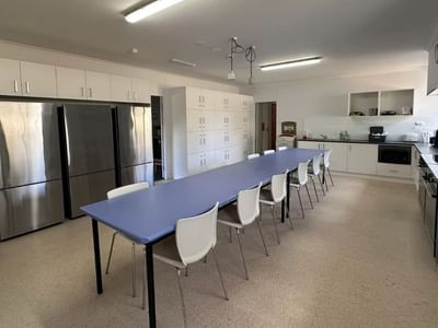 Long dining table and chairs in a kitchen at La Trobe University - Orde House.