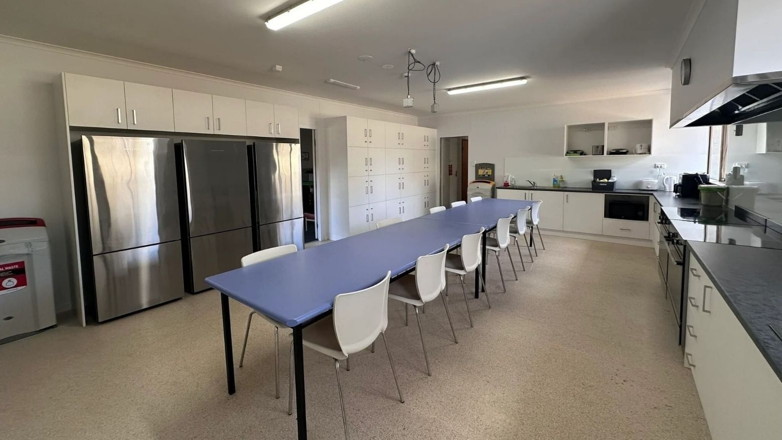 Long dining table and chairs in a kitchen at La Trobe University - Orde House.