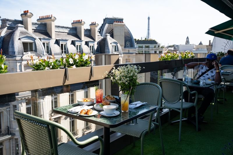 Rooftop terrace with breakfast table and Eiffel Tower views at Warwick Paris Champs Elysées