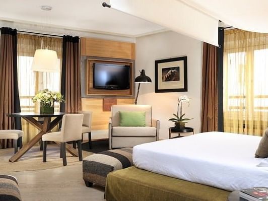 Bed with a TV & table in Deluxe Suite at Rome Luxury Suites
