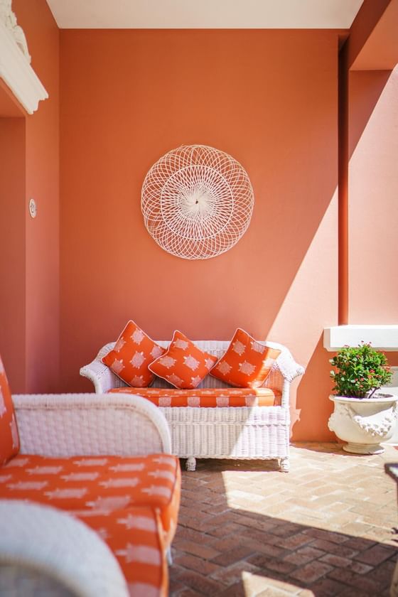 Orange and white pillows arranged with sofa in patio at Royal Palms Hotel