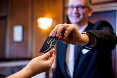 A friendly hotel staff member hands a key card to a guest at the Royal on the Park Hotel