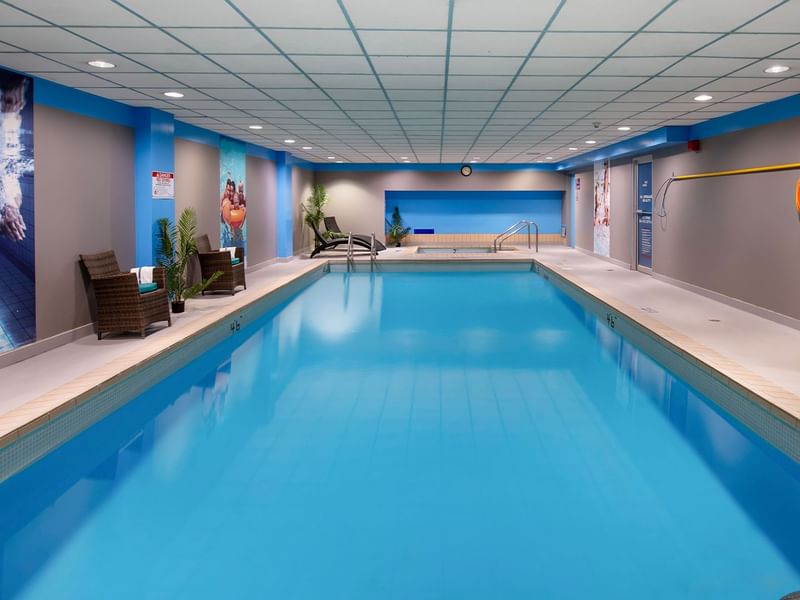 Indoor swimming pool in Coast Prince George Hotel by APA with lounge chairs