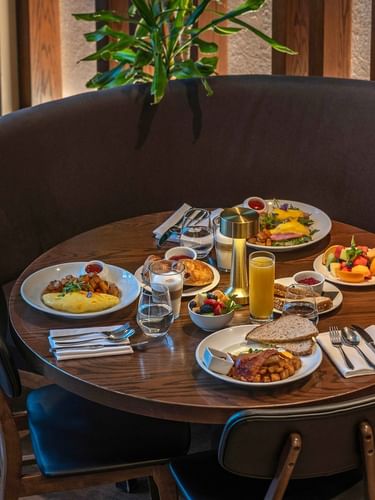 Breakfast spread with omelets and fresh fruit placed on a round table by curved seating at Warwick Le Crystal Montreal