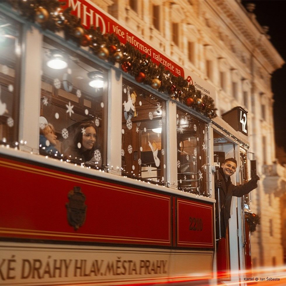 Lidé ve vánoční tramvaji 42 s ozdobami a světly večerem