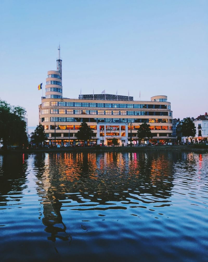 Modern building with glass windows and Belgian flag by the water at Hotel Barsey by Warwick 