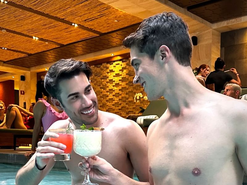 Two men enjoying drinks in a pool at Fiesta Americana