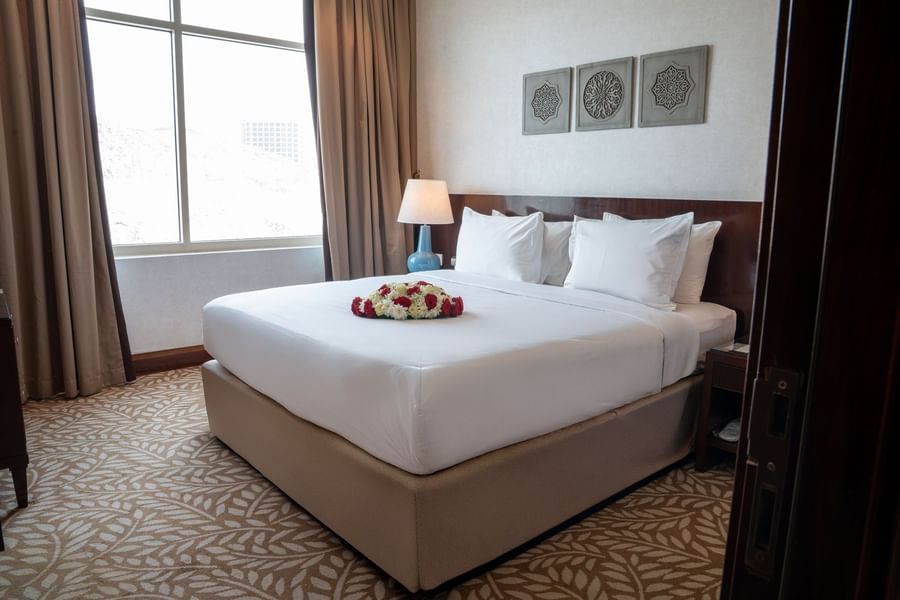 Guest bedroom featuring floral bed decor and a stylish bedside lamp with wall art at Saja by Warwick Makkah