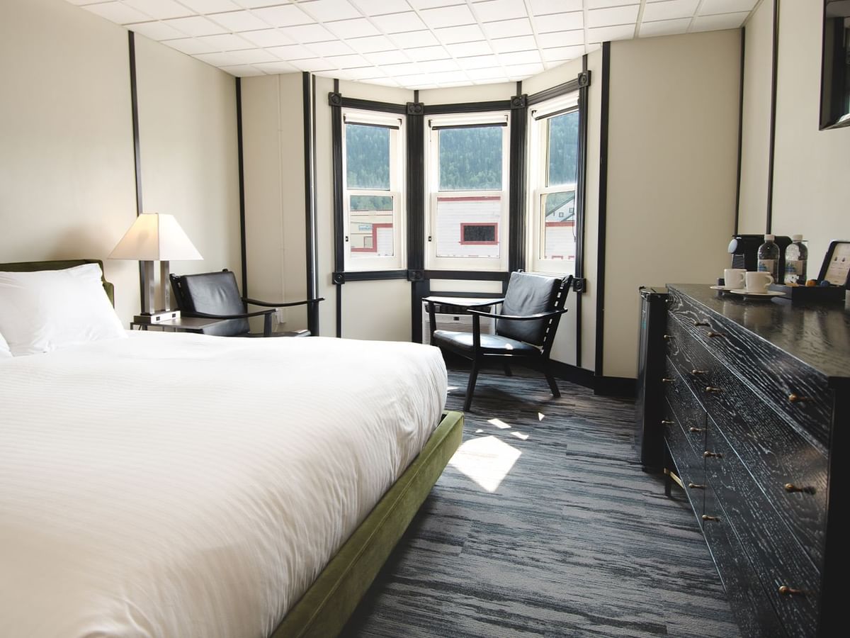 Hotel room with king bed, lamp, night stand, premium coffee, TV, chair, and window