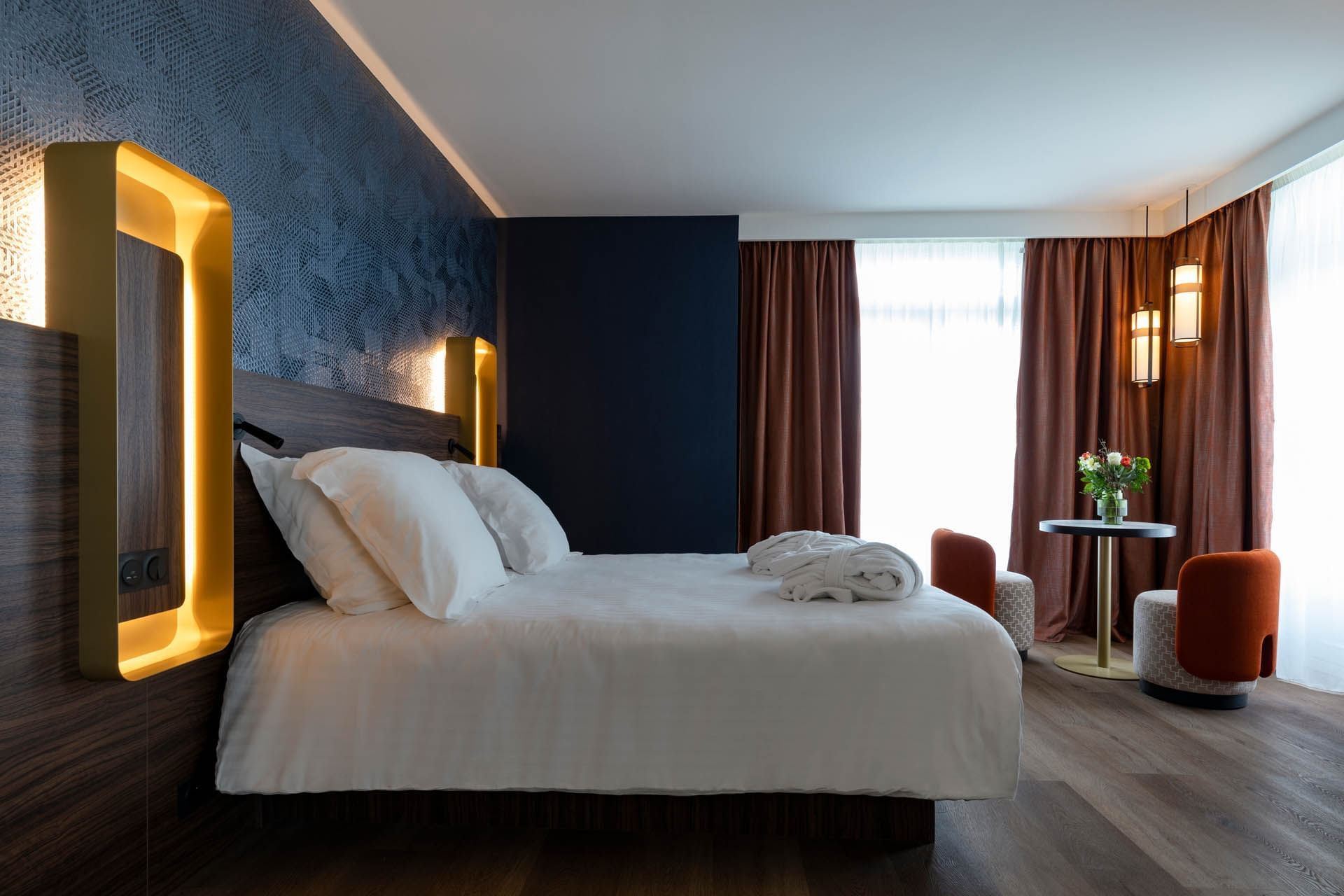 Lit king-size et coin salon dans une chambre à l'Oceania Le Conti Brest
