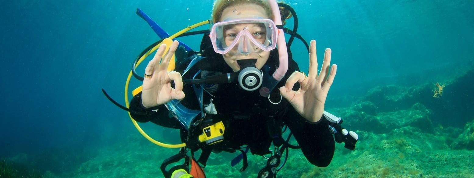 Young woman scuba diver signals okay at Daydream Island Resort