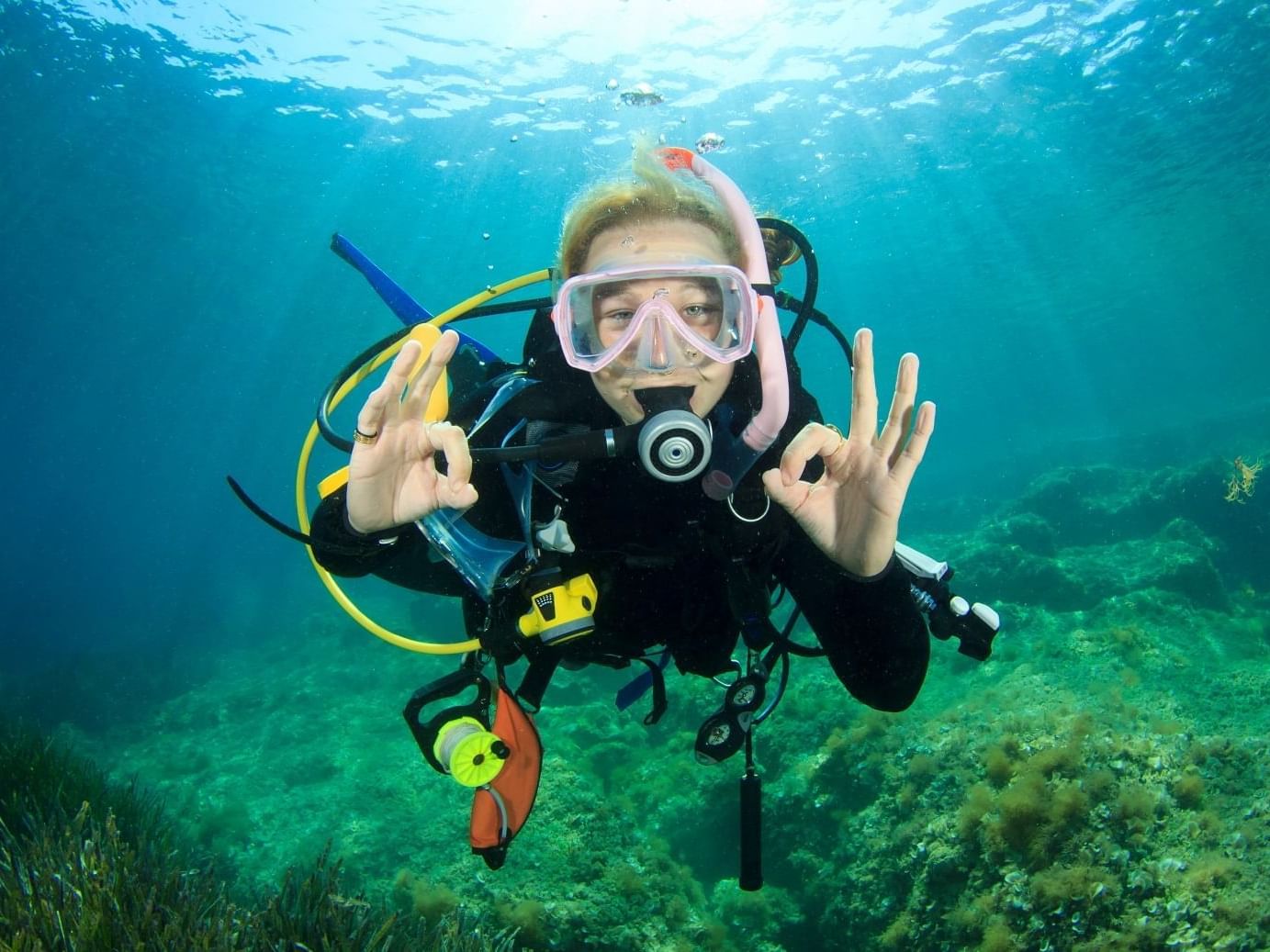 Young woman scuba diver signals okay at Daydream Island Resort