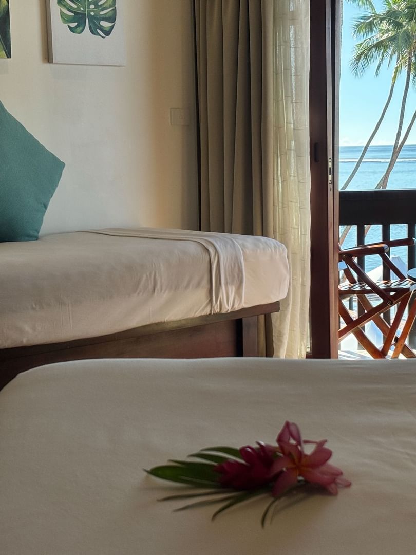 Daybed by a balcony overlooking the ocean and palm trees under a bright sky at Warwick Hotels & Resorts