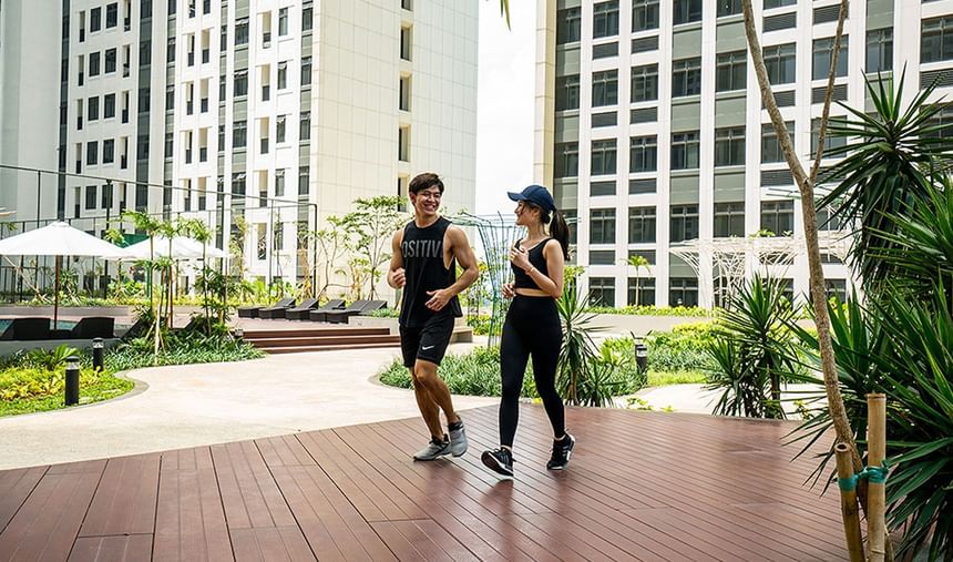 A couple posing with gym outfits on a wooden floor area outdoors at LK Cikarang Hotel & Residences