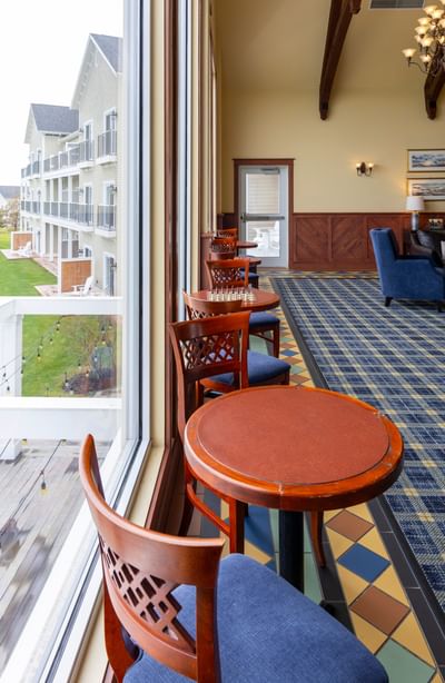 Wooden tables and blue chairs by a large window overlooking Rodd Crowbush Golf & Beach Resort