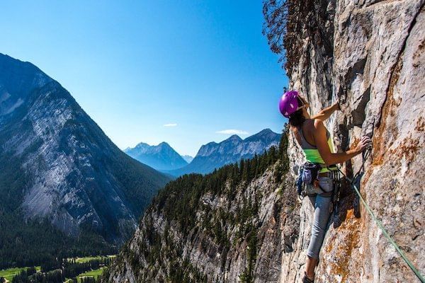 A woman rock climbing on the side of a mountain