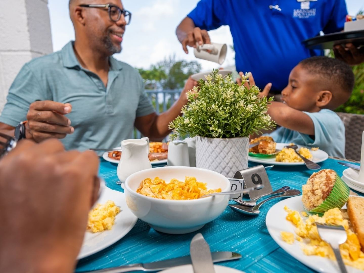Family enjoying a breakfast meal with a waiter serving at Savannah Beach Hotel.