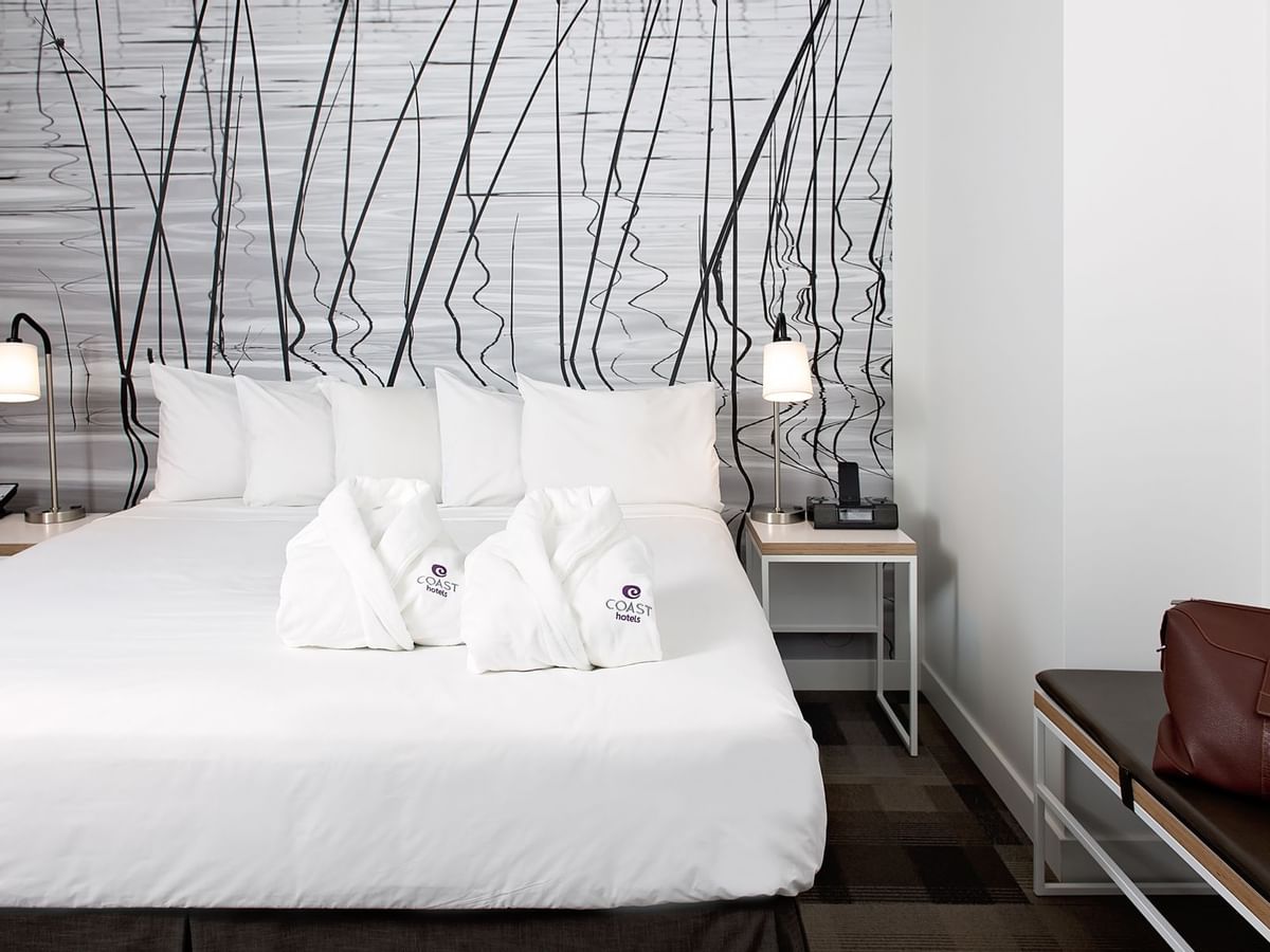 Robes and bed in hotel room with modern artwork