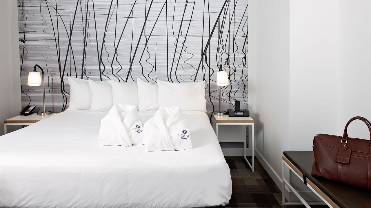 Robes and bed in hotel room with modern artwork