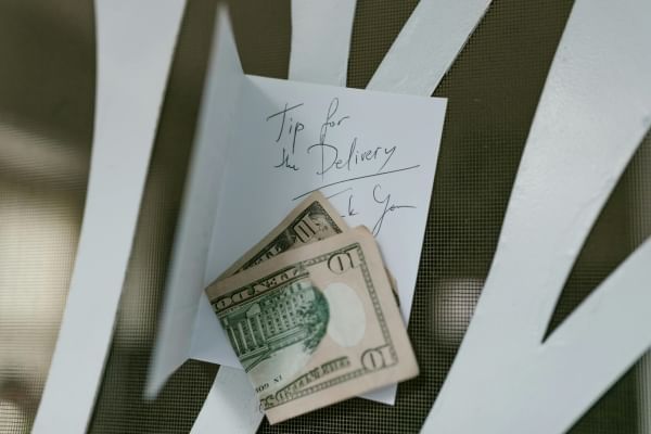 A ten dollar bill attached to a chair with a handwritten note that reads "Tip for the delivery, thank you." Tipping generously is a great thing to do during Random Acts of Kindness Week.