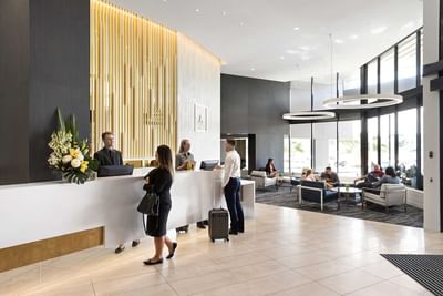 People at the check-in by the lounge area with seating at Alcyone Hotel Residences