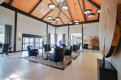 Dark chairs by a circular table under a vaulted wooden ceiling, with wide pillars in a lobby at Rodd Miramichi River