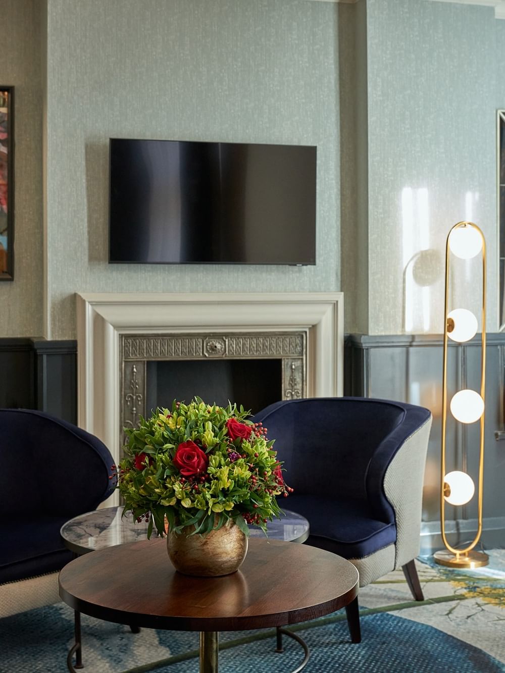 Living area with a fireplace, artwork, and flowers in the Deluxe Room at The Capital Hotel, Apartments & Townhouse