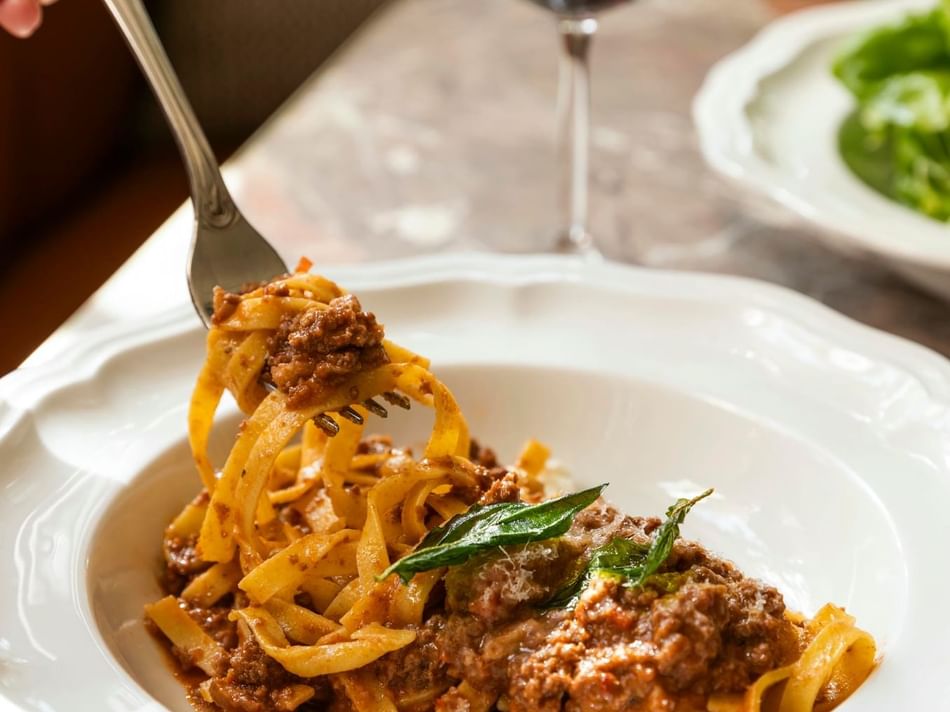 Plate of spaghetti Bolognese topped with grated cheese, served at Bar Remi in Granduca Houston