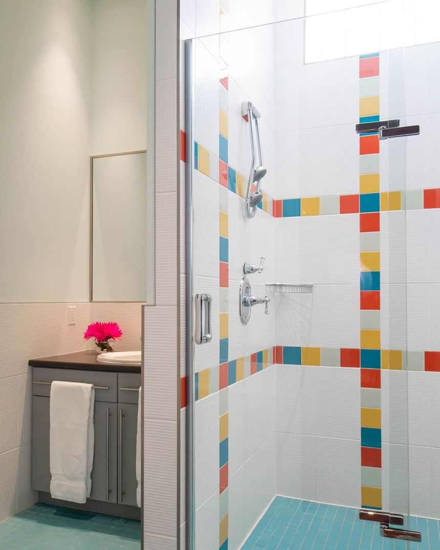 colourful tile in a well lit walk-in shower with pink flower in 