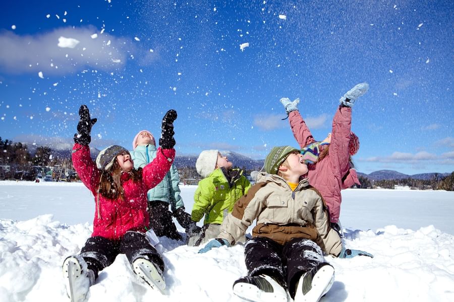 A group of happy children playing and throwing snow in the air on a sunny winter day near High Peaks Resort