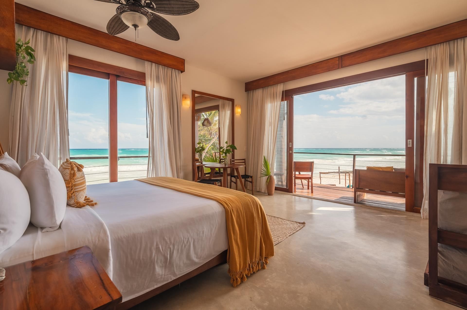 Bright airy suite at La Zebra Hotel with a king bed wooden accents and an ocean-view balcony overlooking the sea