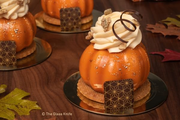 A pastry resembling a pumpkin topped with whipped cream and garnished with decorative chocolates. The Pumpkin Pastry from The Glass Knife, a pumpkin treat in Orlando.