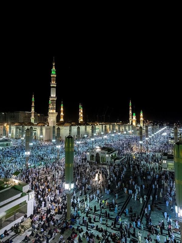 Night view of the crowded Al-Masjid an-Nabawi courtyard with illuminated tall minarets at Saja Warwick Madinah