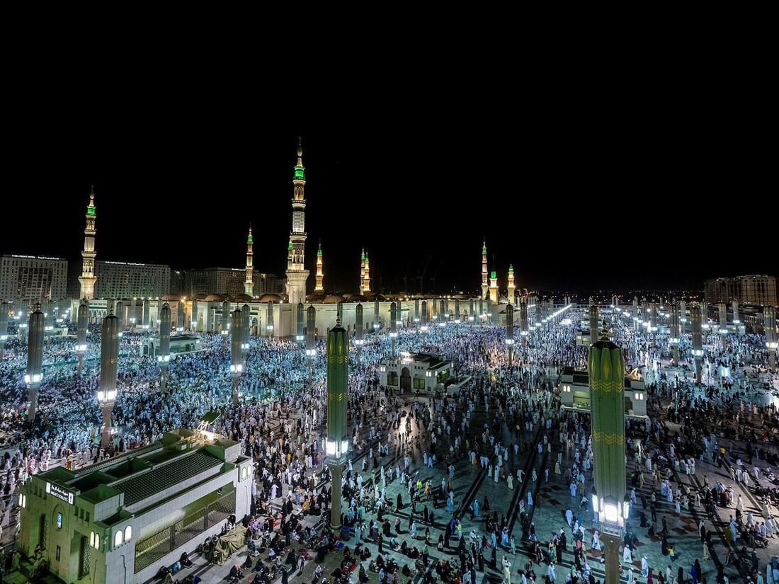 Night view of the crowded Al-Masjid an-Nabawi courtyard with illuminated tall minarets at Saja Warwick Madinah