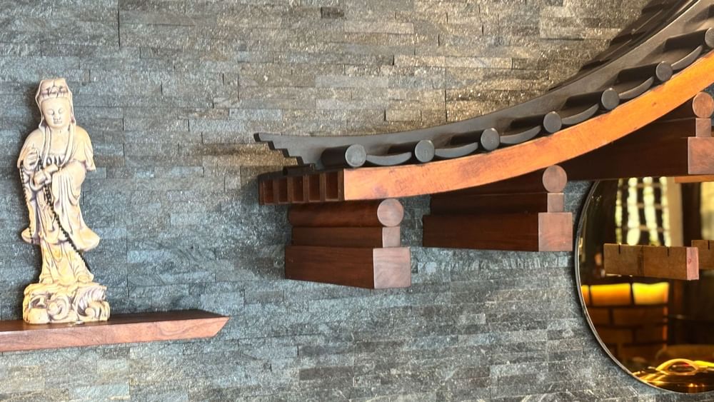 A wall with a Buddha statue and wooden structure at Sazanami in Korolevu at Warwick Fiji Resort and Spa.
