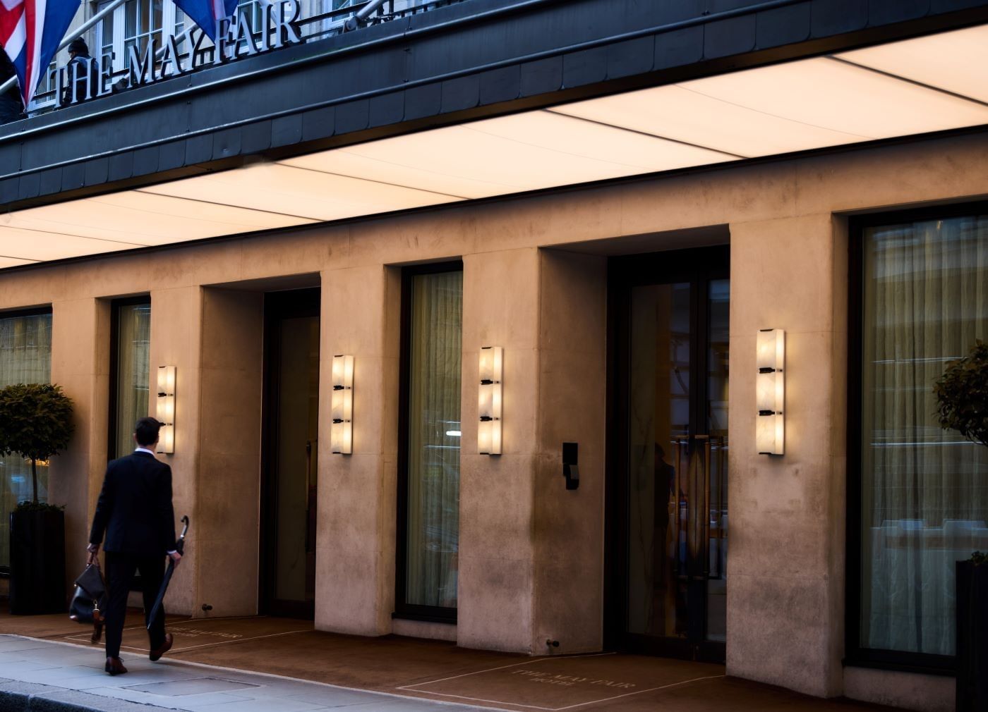 Man with umbrella walking into the main entrance of The May Fair Hotel
