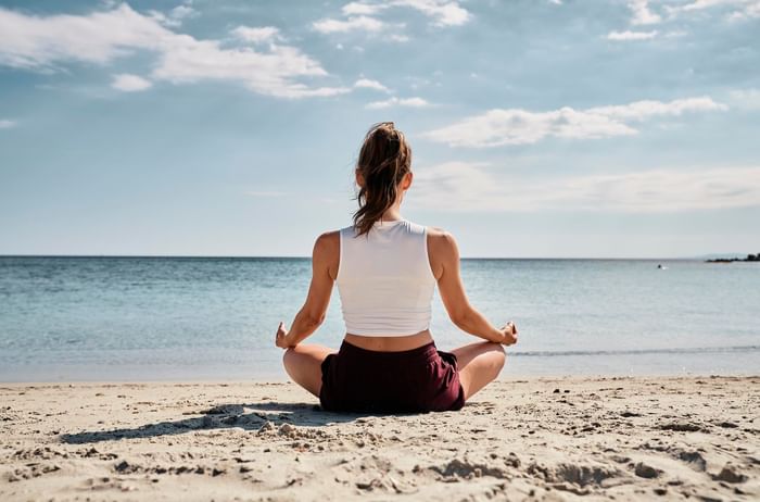 A woman meditating on the beach at Falkensteiner Hotels