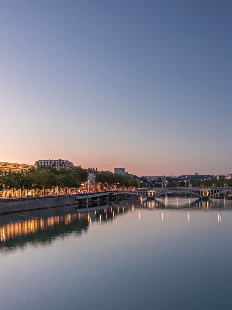 Illuminated historic dome building by a tranquil river at dusk near Warwick Reine Astrid - Lyon